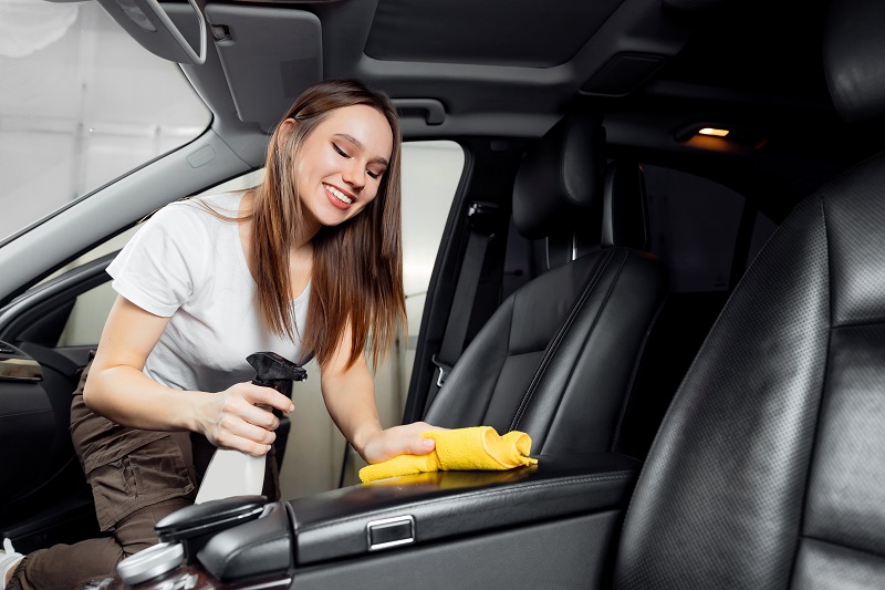 Mulher realizando a higienização interna do carro