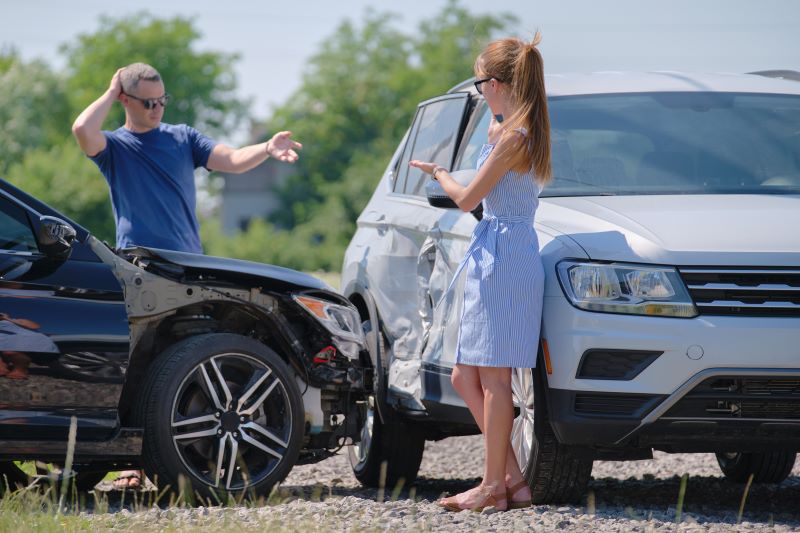 homem e mulher discutem ao lado de seus carros batidos
