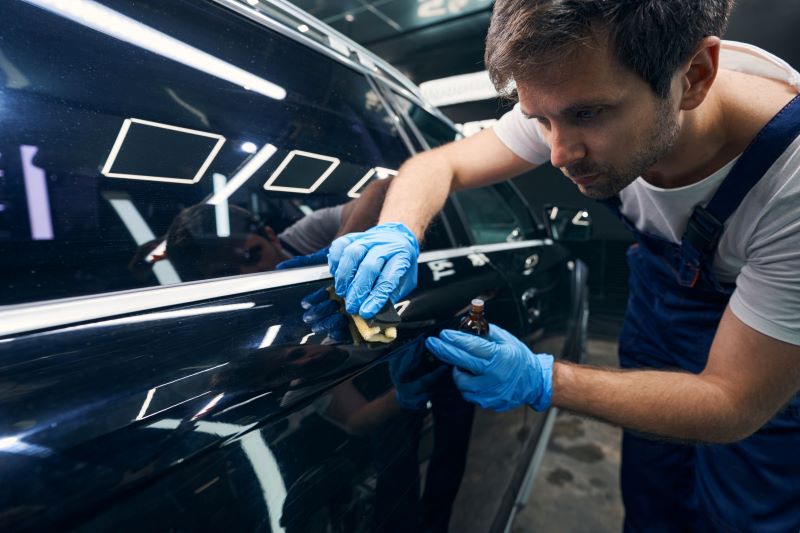 detalhamento automotivo​: homem usando luvas e revitalizando a pintura de carro azul-marinho