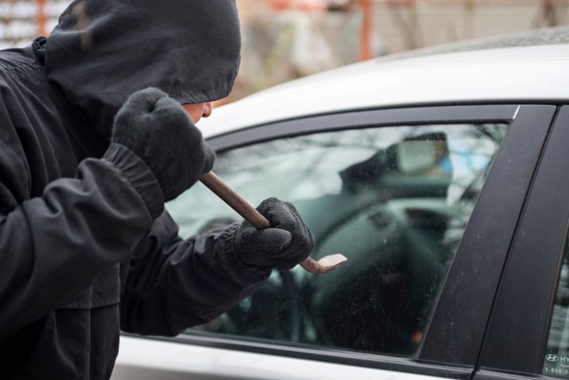 película antivandalismo​: homem tentando arrombar janela de carro com pé de cabra